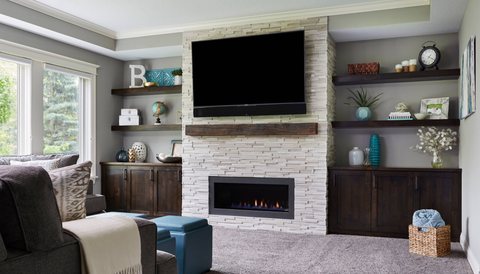 Living room with a stacked-stone fireplace and built-in shelving, by MDR Design-Build-Remodel
